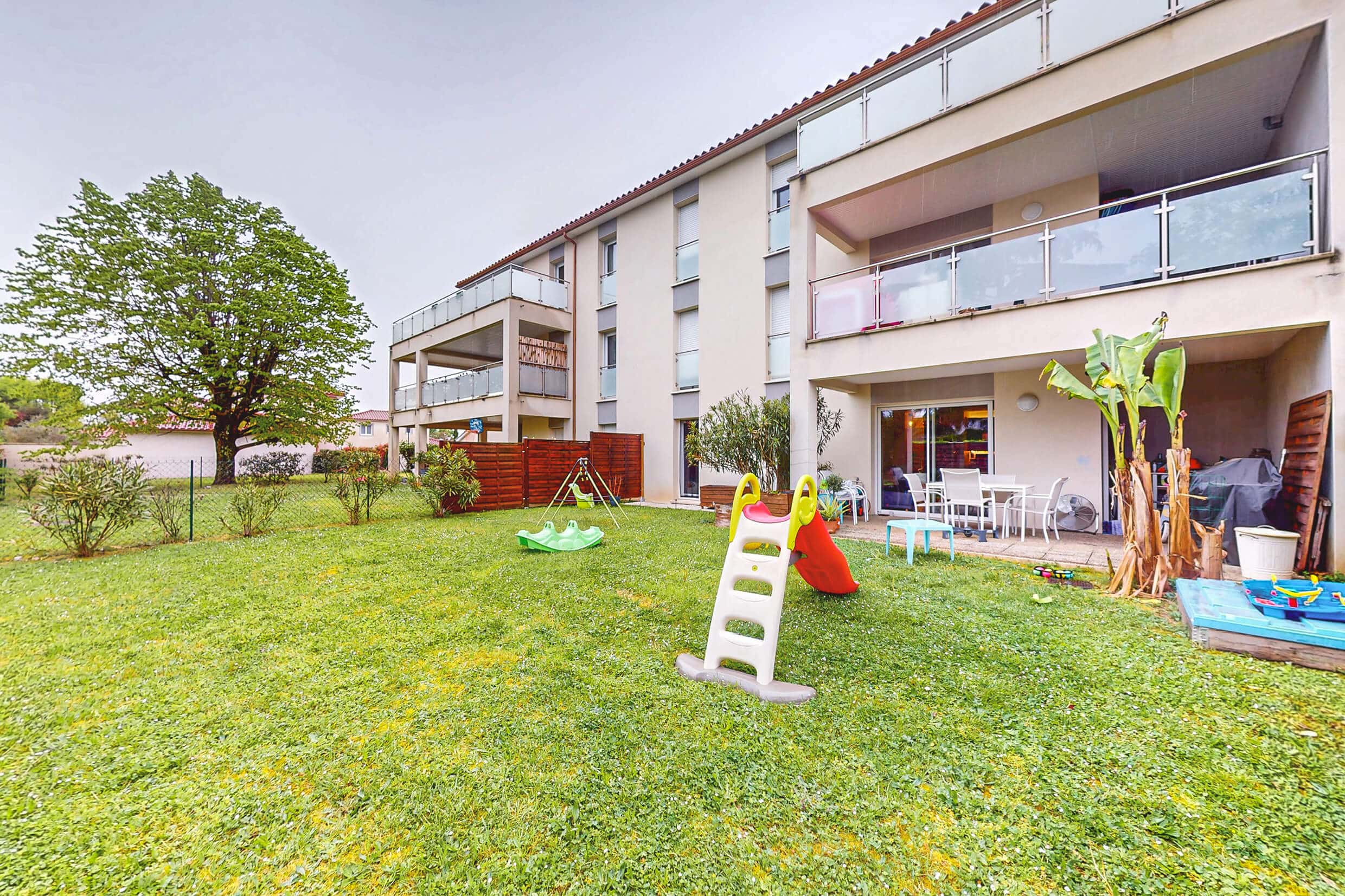 Vue du jardin sur l’appartement et la résidence récente et bien entretenue à Meyzieu