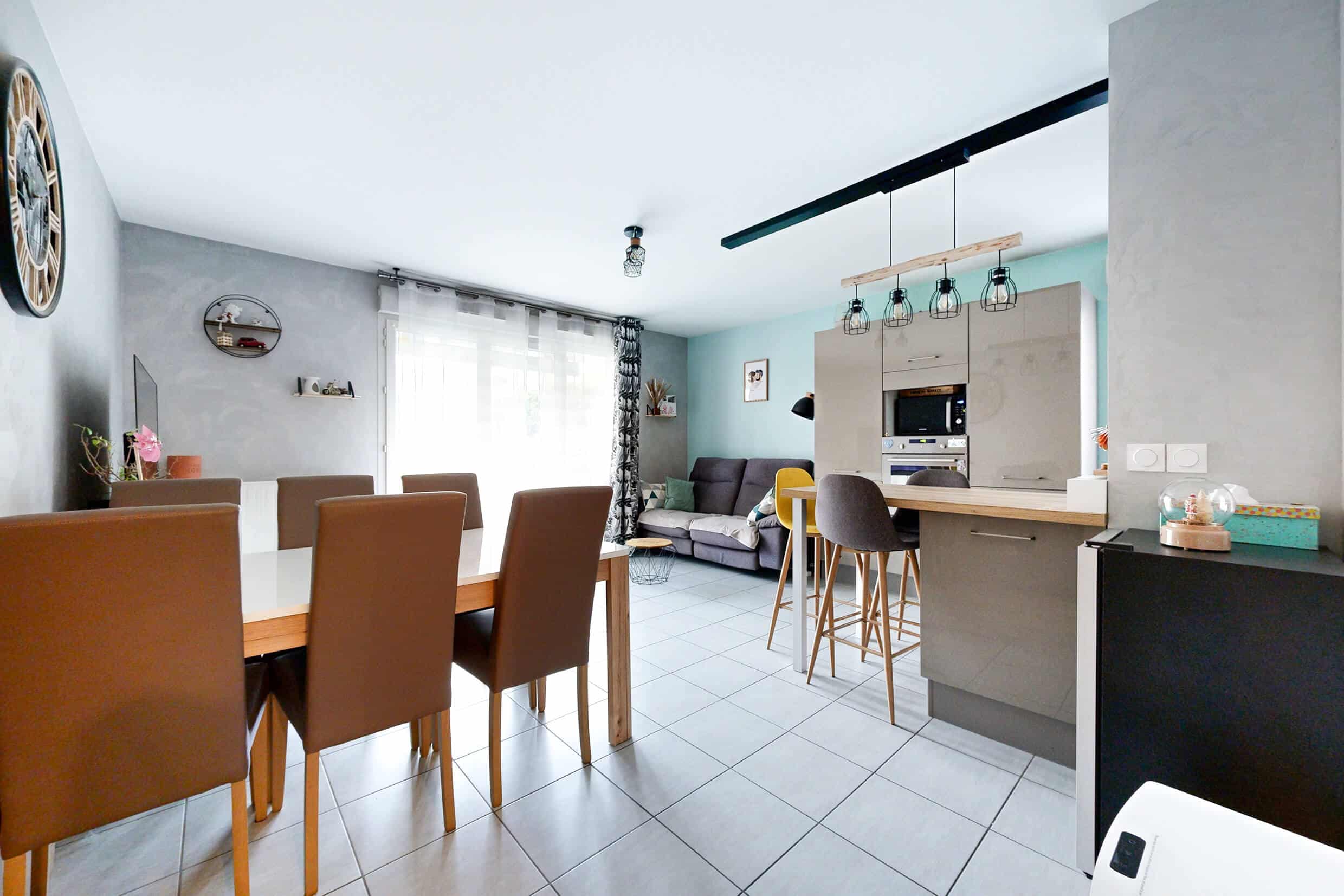 Salon lumineux avec cuisine ouverte dans un appartement vendu à Meyzieu – décoration contemporaine et belle luminosité