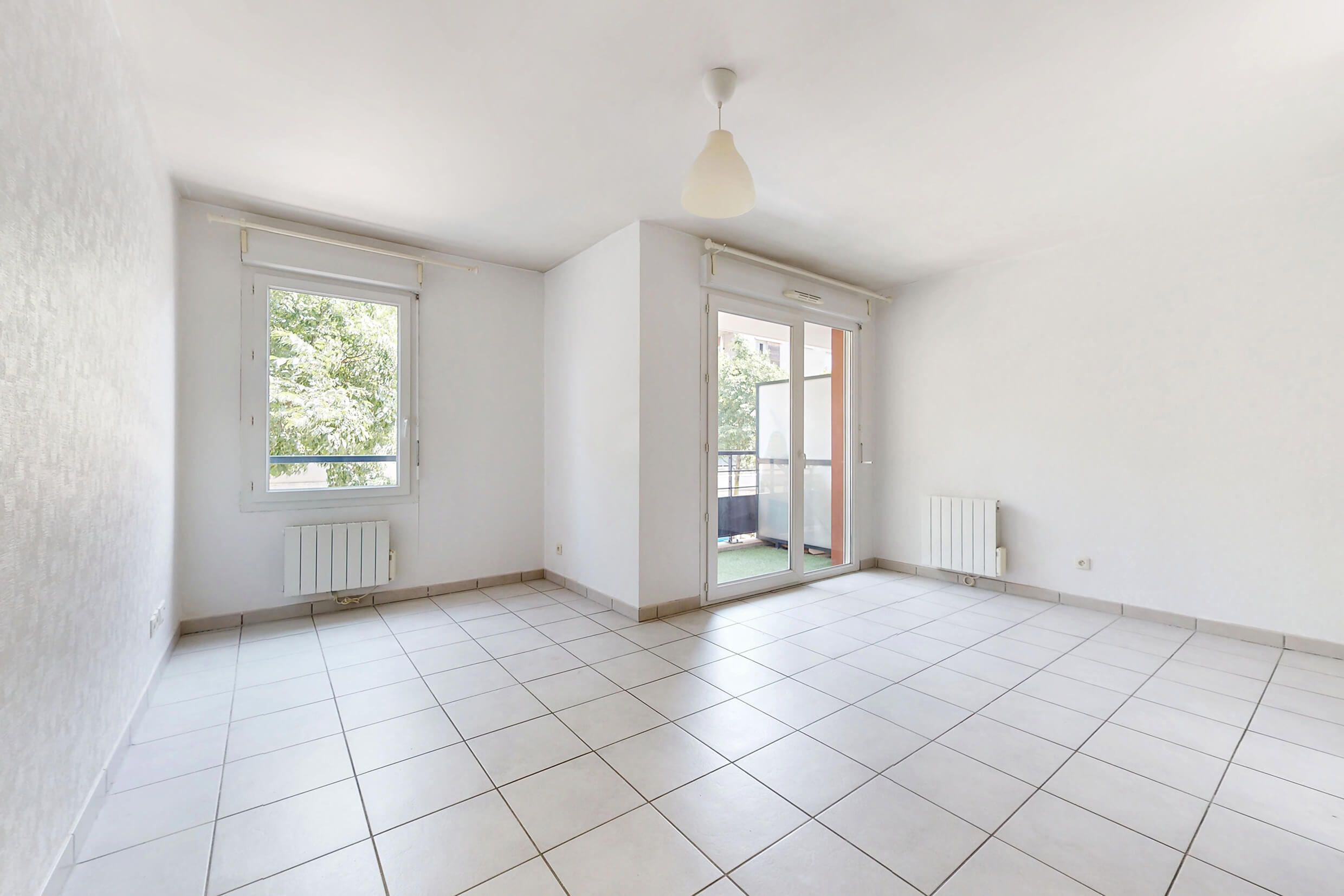 Salon lumineux avec accès direct au balcon dans un appartement T2 à Meyzieu