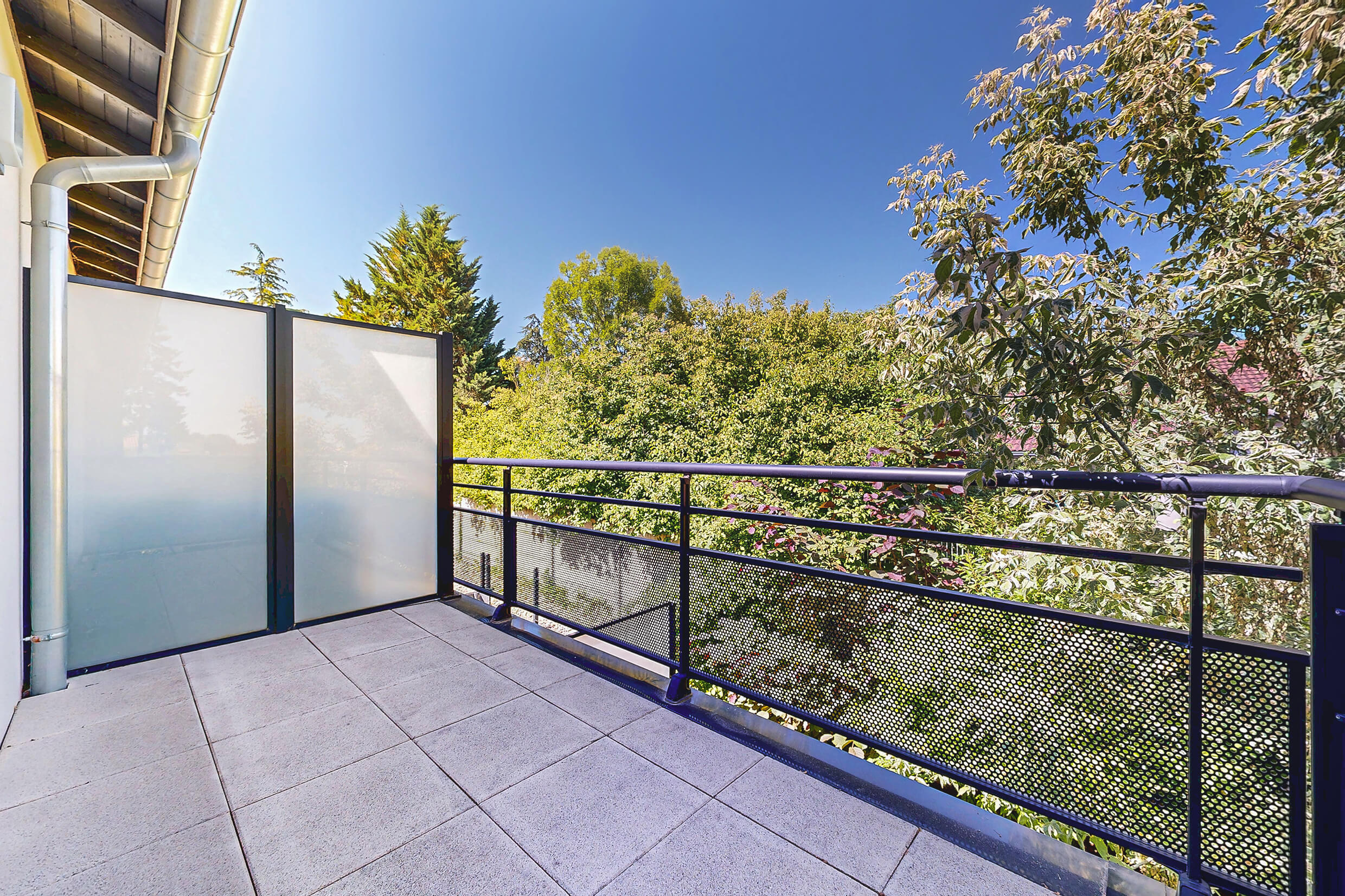 Vue dégagée depuis le balcon d’un appartement T2 à Chassieu, sans vis-à-vis et entouré d’arbres
