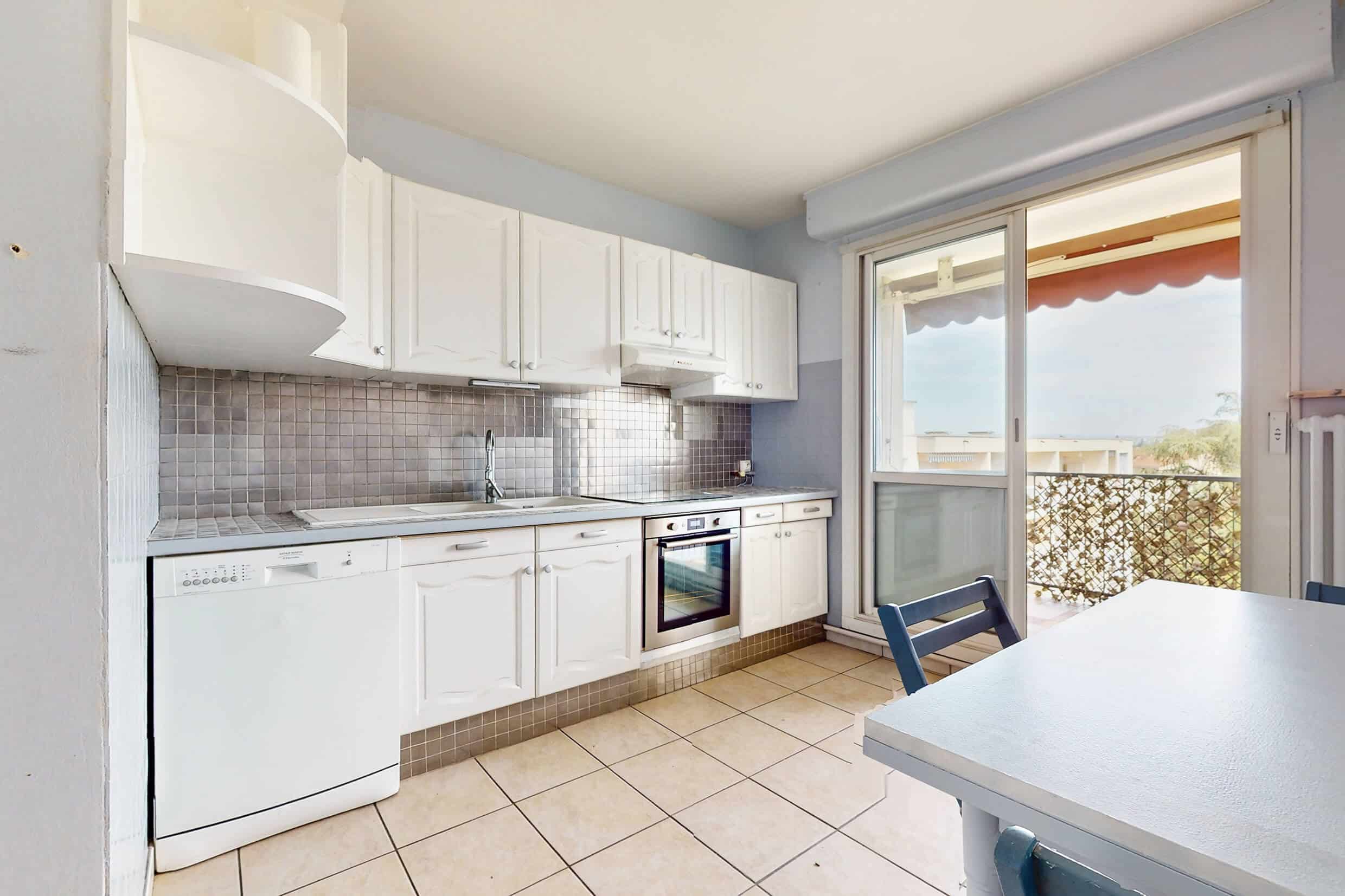 Grande cuisine lumineuse avec accès direct au balcon dans un appartement à Meyzieu