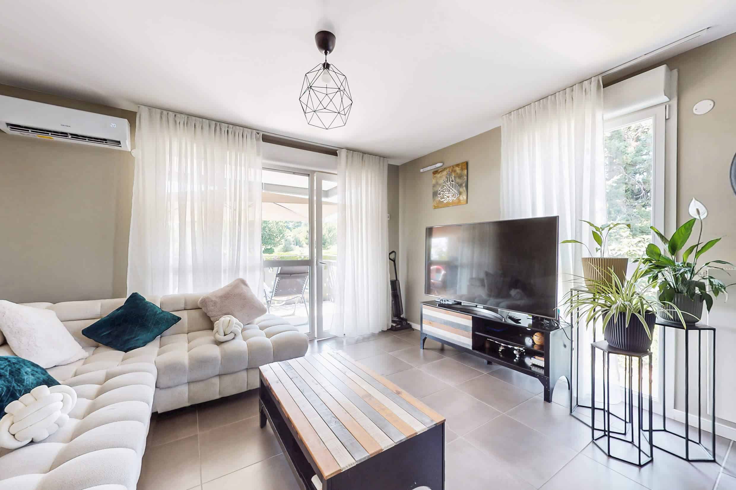 Coin salon cosy avec espace TV et accès direct à un balcon