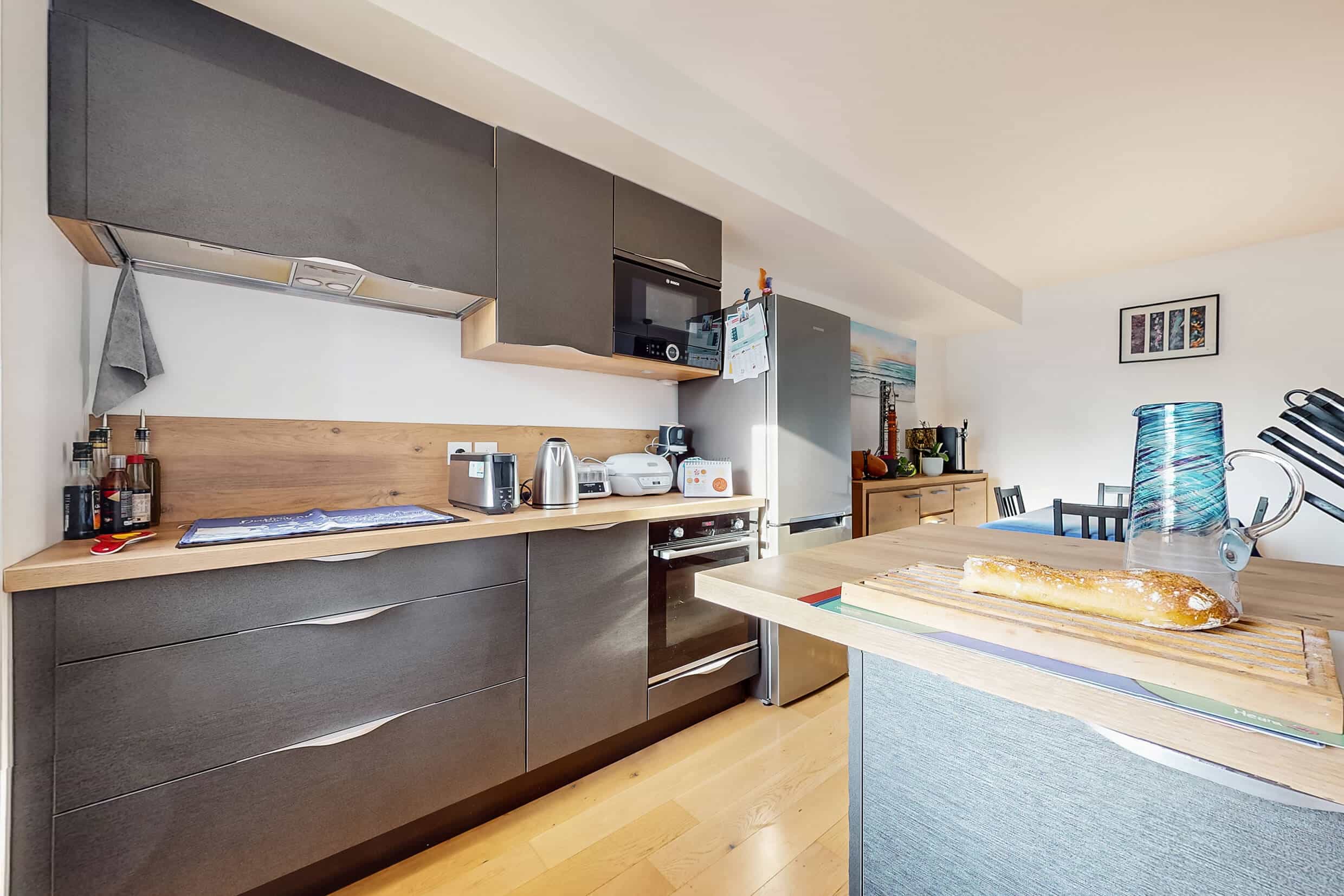 Cuisine équipée ouverte sur le salon dans un appartement T3 récent de 2021 à Vénissieux